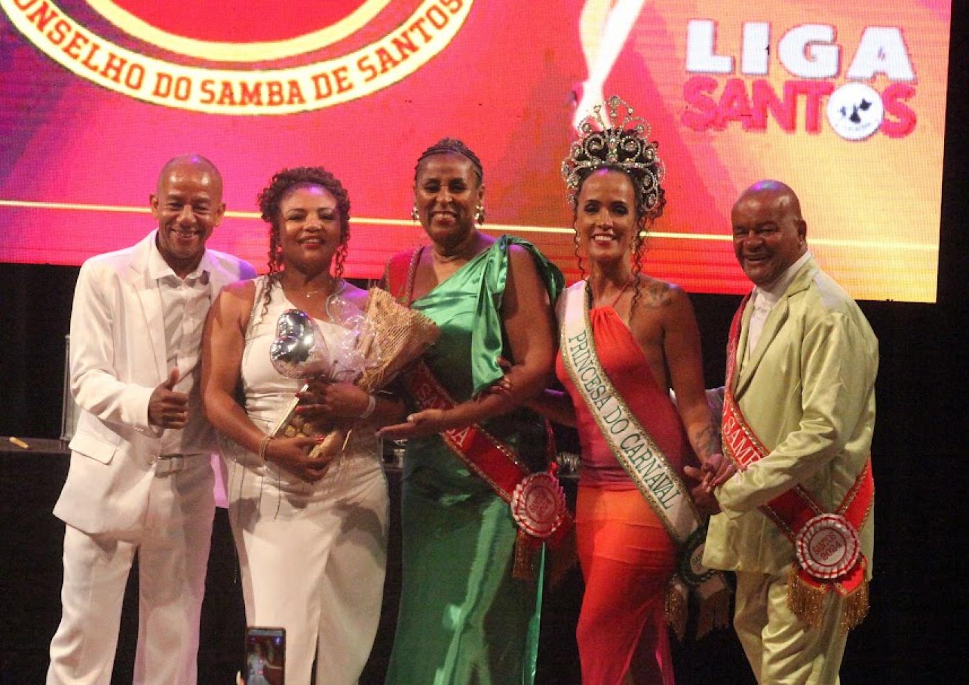cinco pessoa posam para foto. Três delas usam faixa alusiva ao carnaval. #paratodosverem 