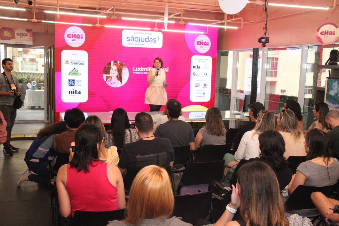 auditório com pessoas sentadas assistindo palestra. #paratodosverem 