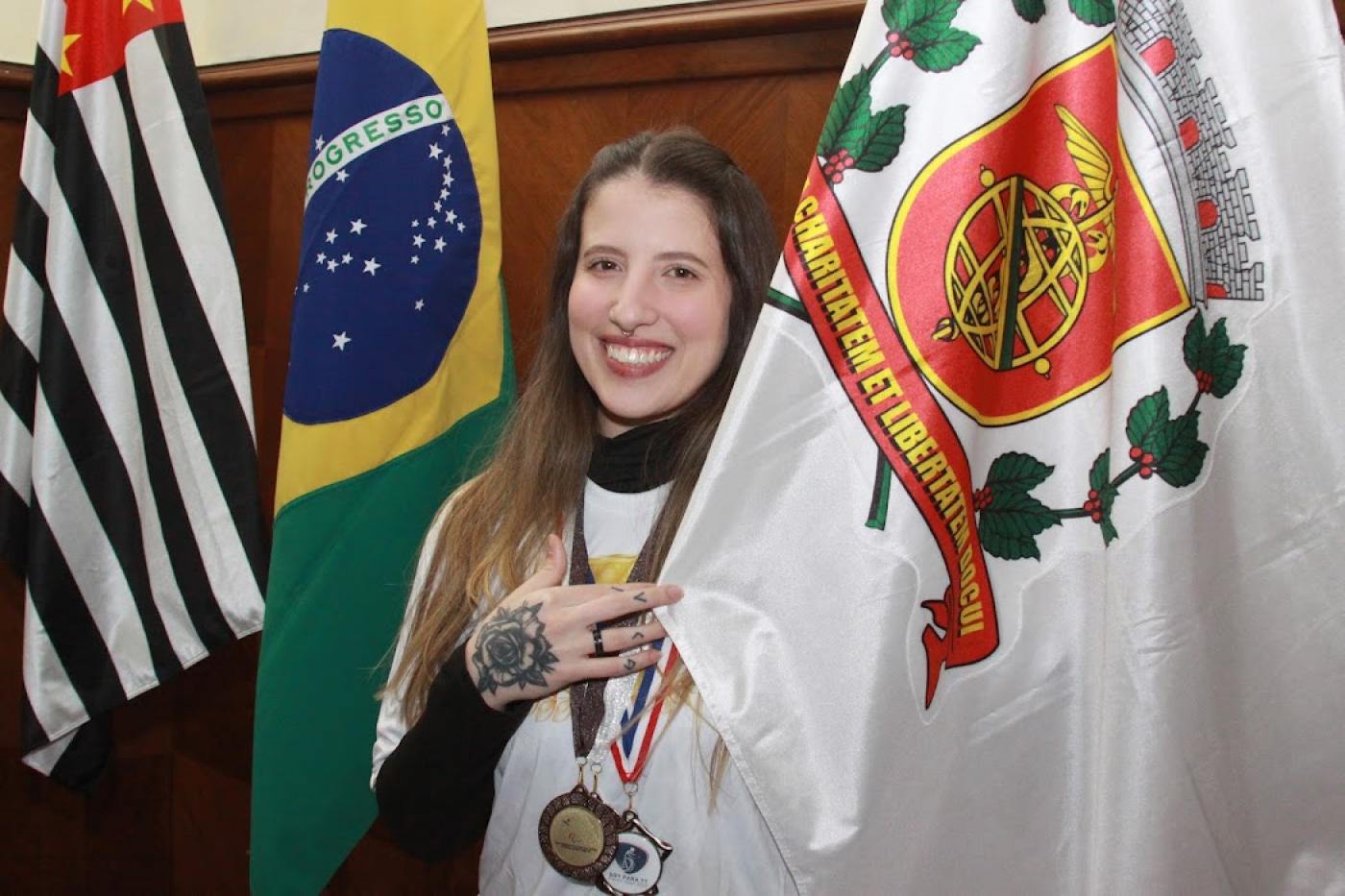 atleta com medalha segurando a bandeira de santos #paratodosverem