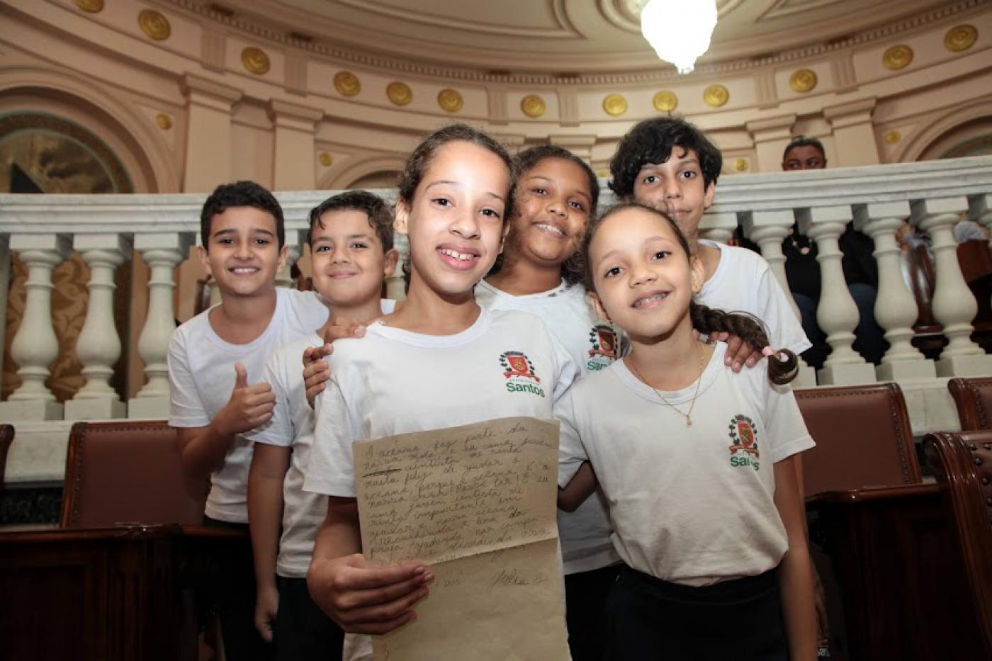 crianças com uniforme do município posam para foto sorrindo na sala princesa isabel. #paratodosverem