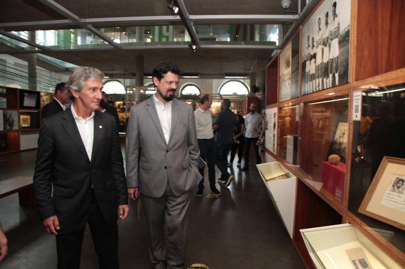 O embaixador e o cônsul apreciam exposição no Museu Pelé. #paratodosverem