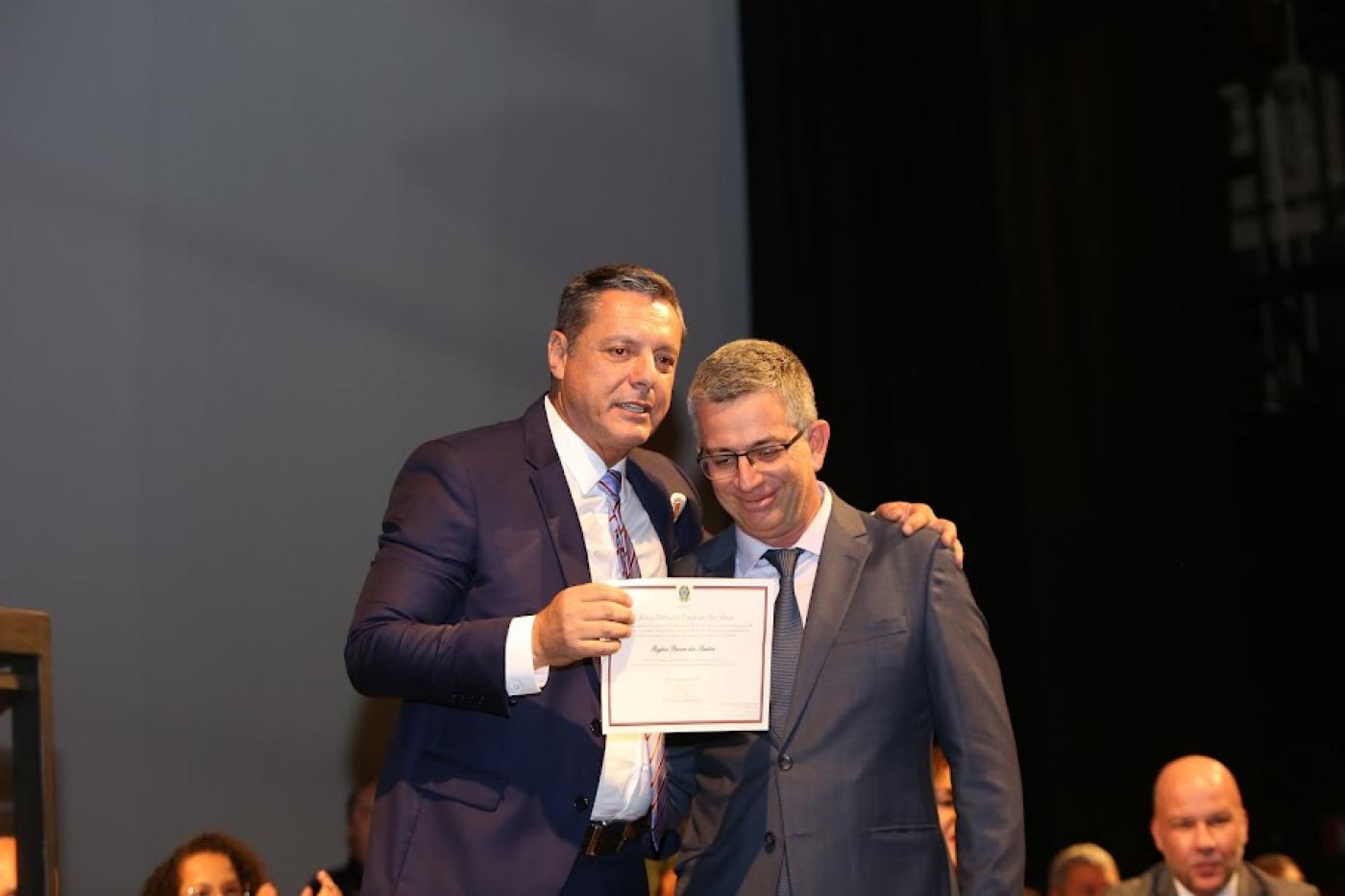 o prefeito segura o diploma e abraça o juiz eleitoral. #paratodosverem