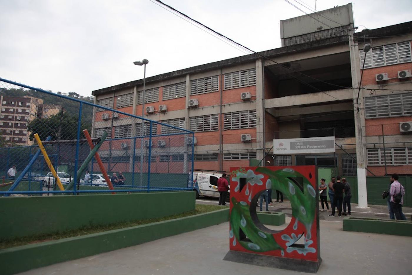 a fachada da escola com um totem estilizado em formato de mureta. #paratodosverem 