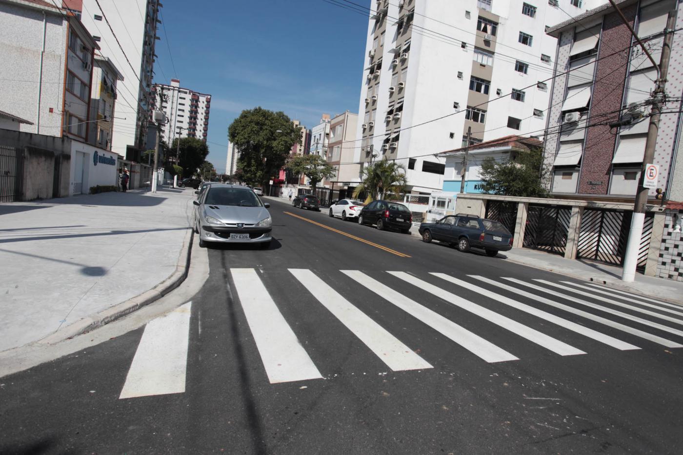 Rua recém-pavimentada, com faixa de segurança pintada. #Pracegover