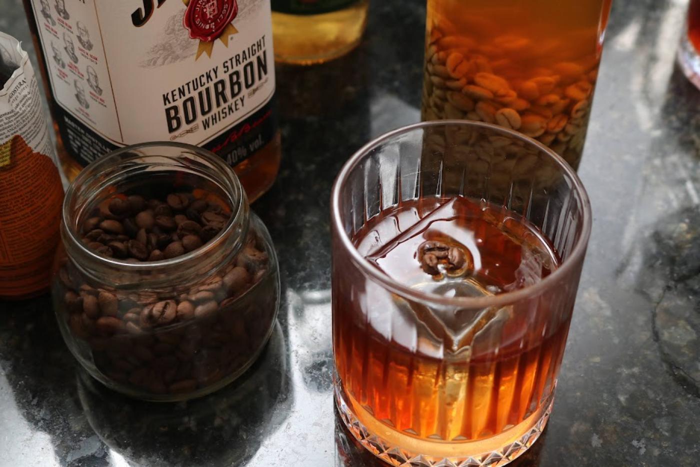 vidro com grãos de café e copo com whiskey. #paratodosverem