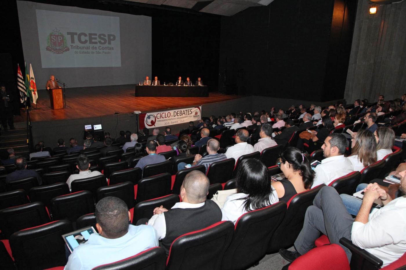 pessoas sentadas no auditório durante o evento #pracegover 