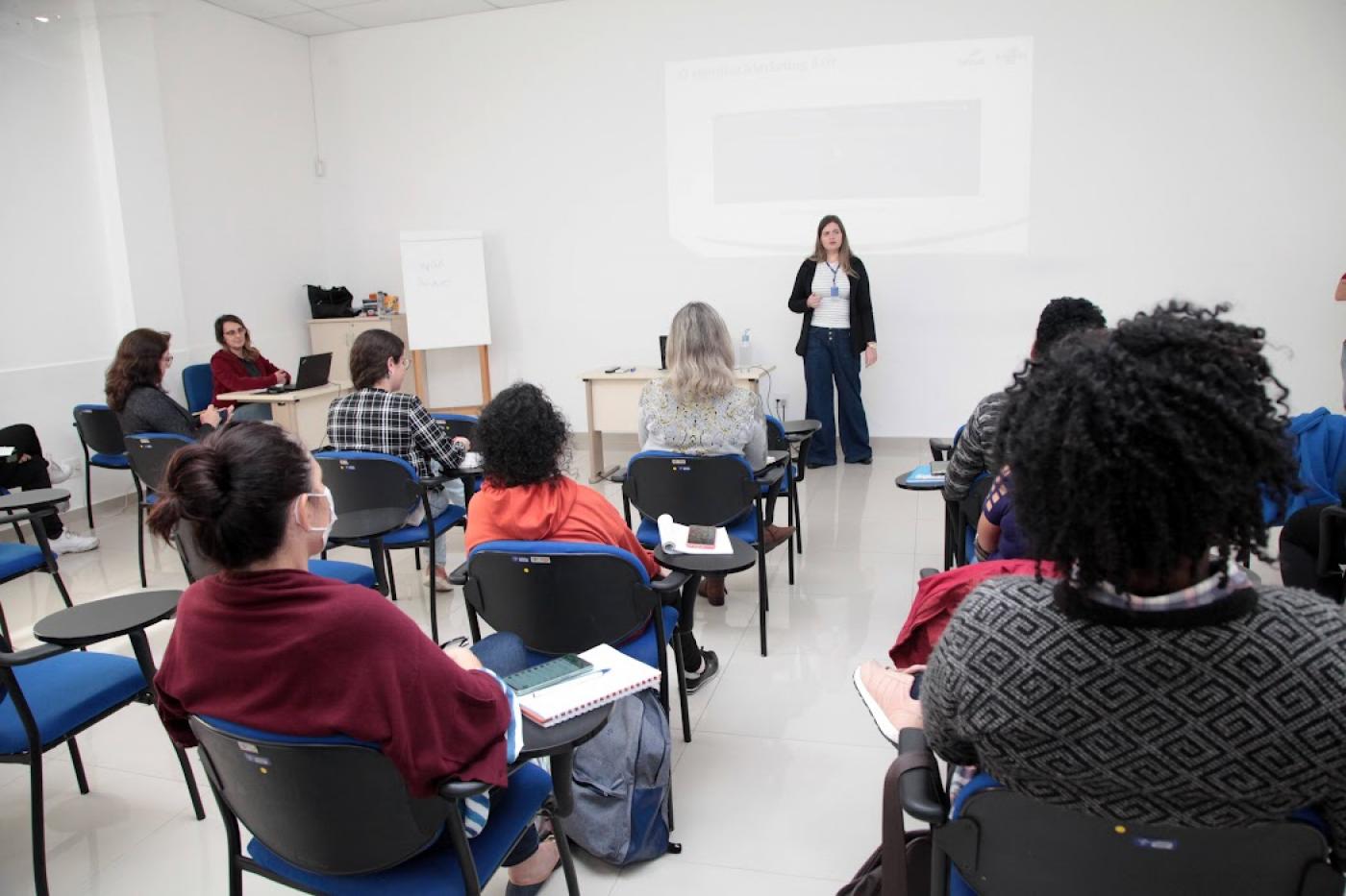 alunas sentadas observam palestrante #paratodosverem