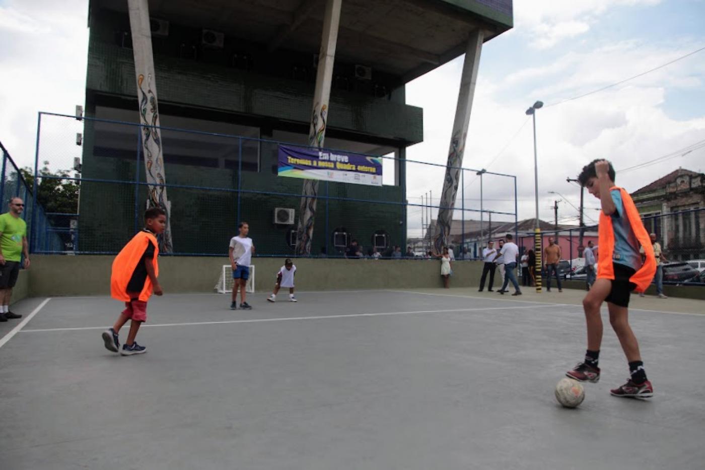 meninos estão jogando gol caixote em quadra recém-aberta. #paratodosverem