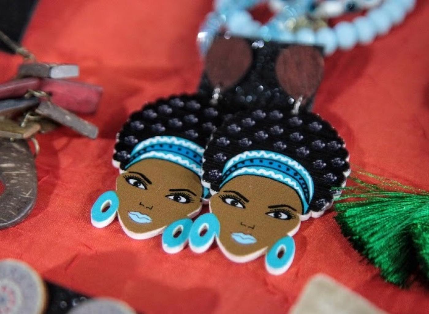 brincos com imagens do rosto de mulher negra, com adereço nos cabelos e brincos. #paratodosverem 