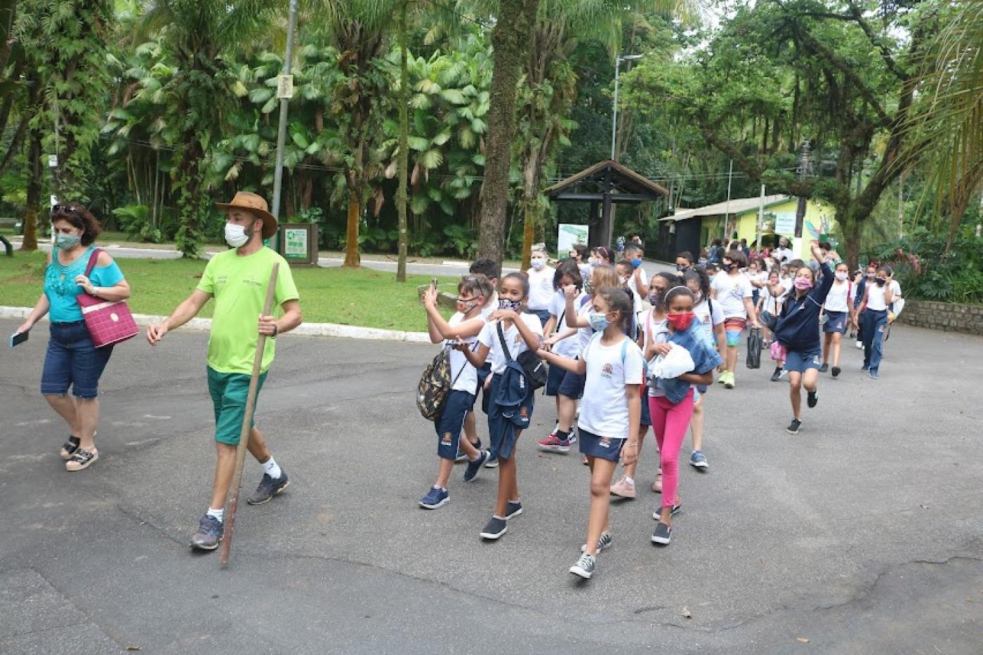 Crianças com instrutor andam em fila no parque #paratodosverem