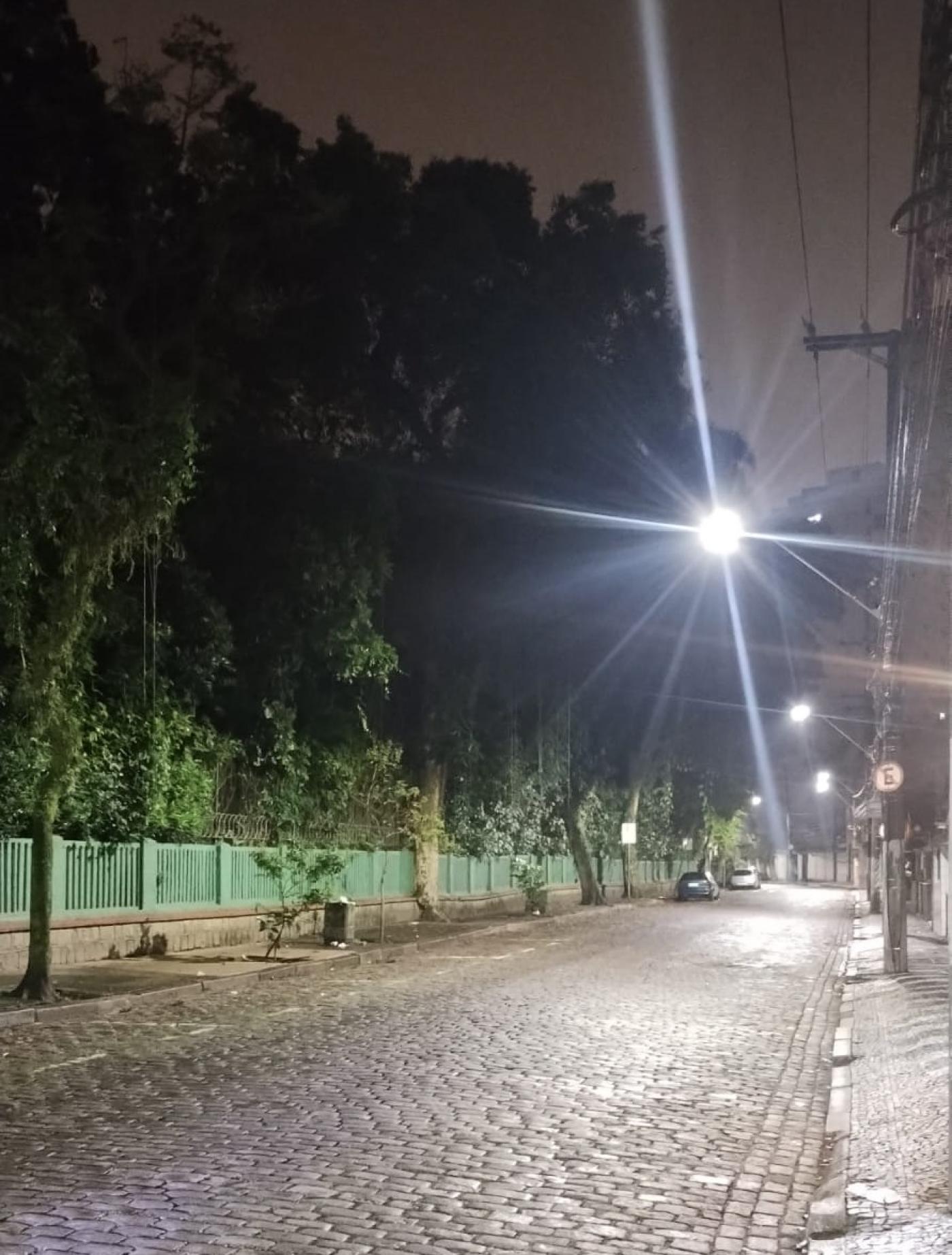 rua à noite com ponto de luz reluzindo no alto e ao fundo. #paratodosverem 