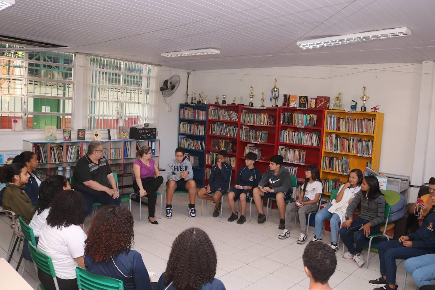 alunos em círculo com jornalista #paratodosverem 
