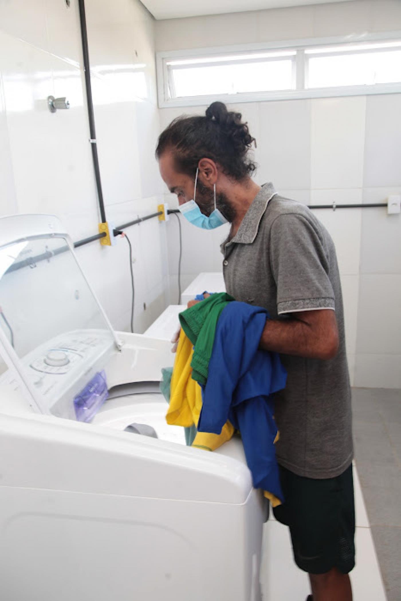 Homem retira roupas de máquina de lavar. #pratodosverem