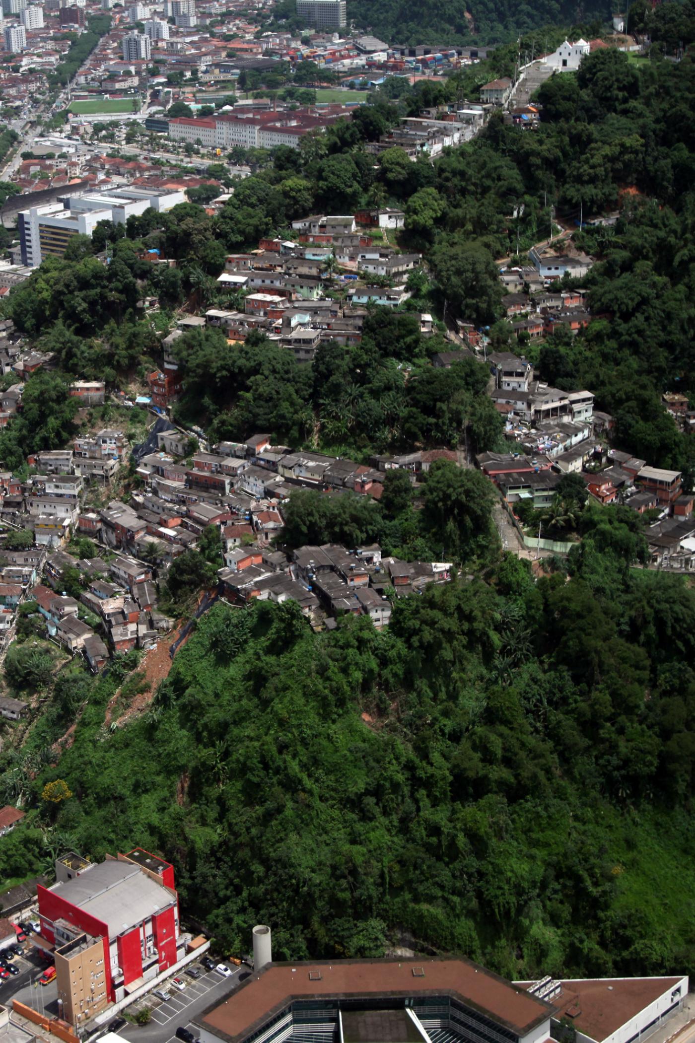 Vista geral de morro com diversas moradias. #paratodosverem