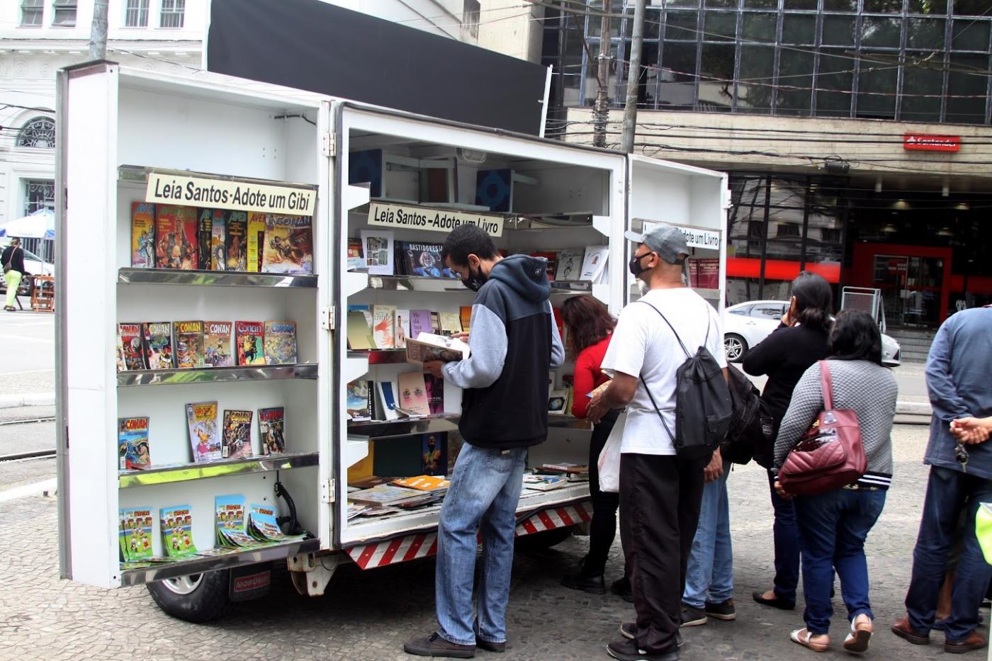 Rapaz lê livro em display no leia santos #paratodosverem 