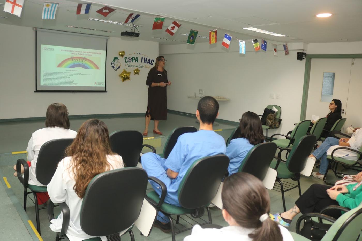 pessoa fala em sala de aula com pessoas sentadas #paratodosverem