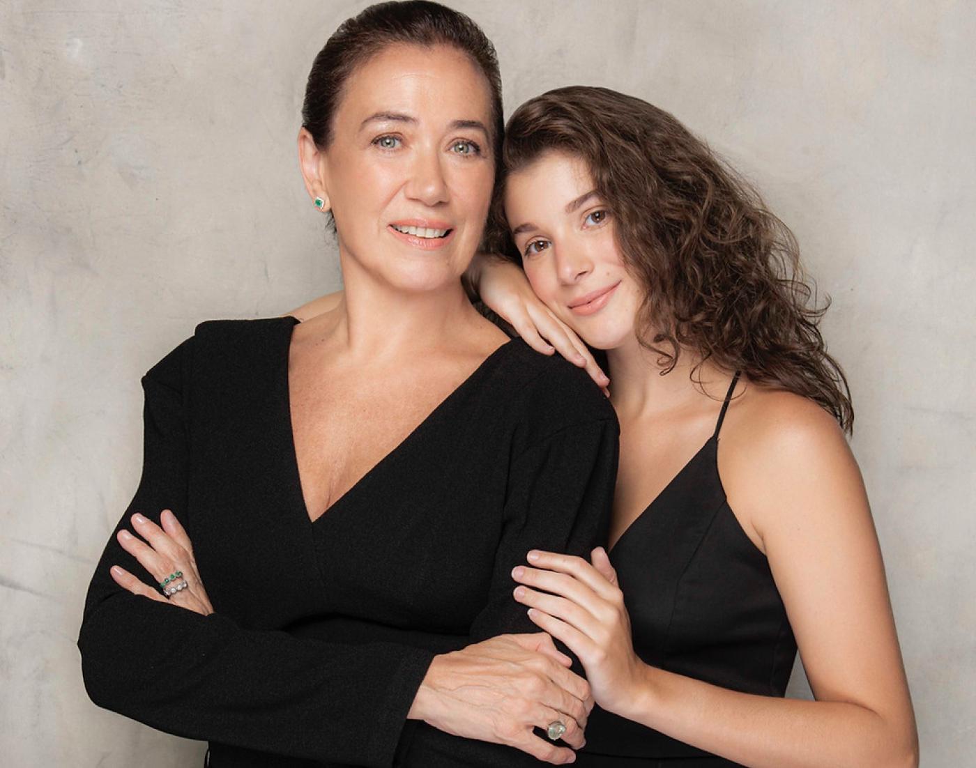 Lilia Cabral e a filha Giulia posam juntas para foto. A filha está atrás da mãe com as mãos no ombro e no braço direito. #paratodosverem