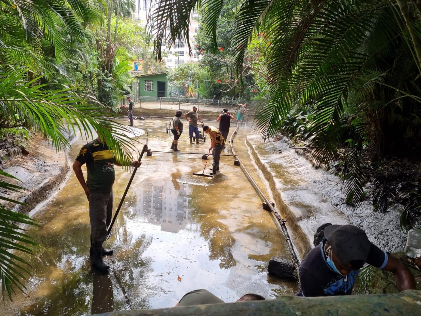 homens estão dentro de lago com pouca água. #paratodosverem