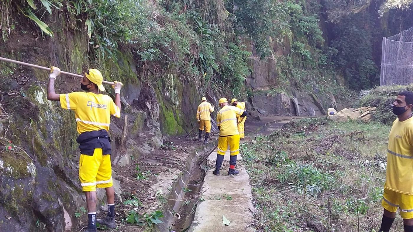 Homens realizam limpeza na encosta do morro. #paratodosverem