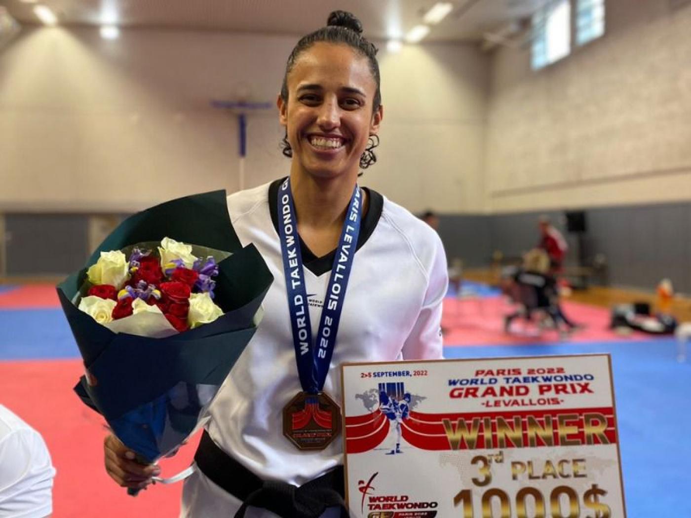 Gabriele exibe premiação e flores com medalha no peito. #paratodosverem