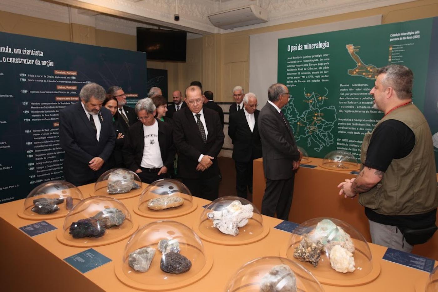 Grupo observa minerais e paineis da exposição sob supervisão de guia. #pratodosverem 