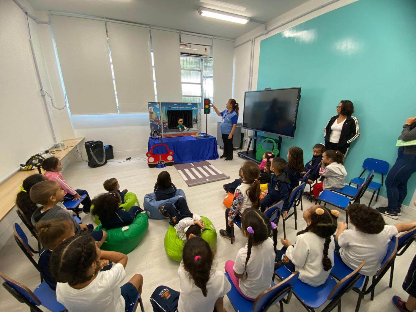 crianças estão sentadas em sala assistindo a um teatro de fantoches. #paratodosverem 