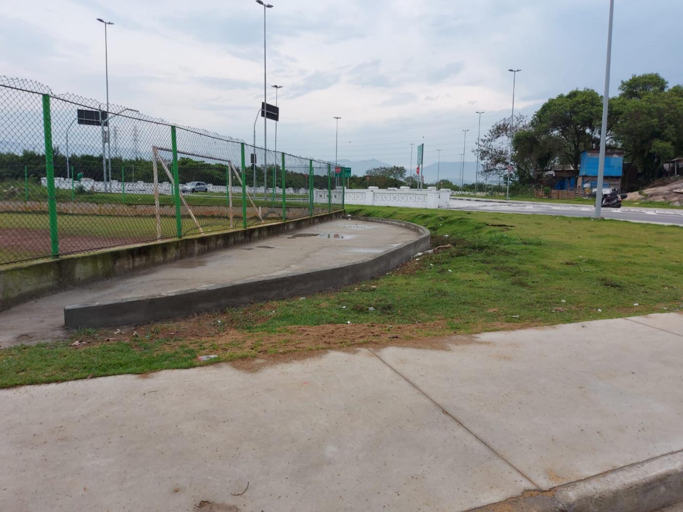 área com calçada, gramado e alambrado à esquerda. #paratodosverem