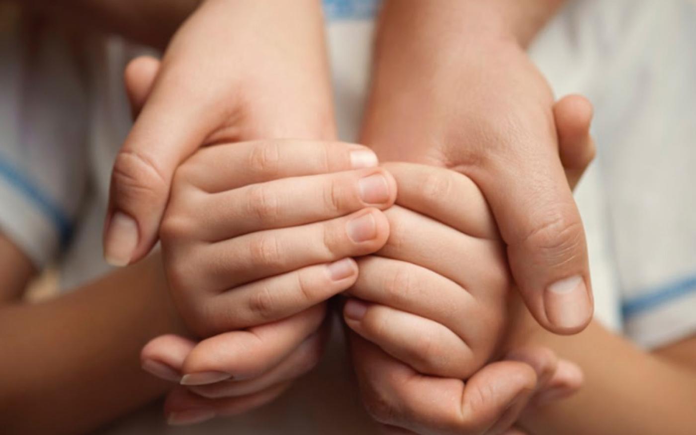 mãos de adulto seguram mãos de criança. #paratodosverem