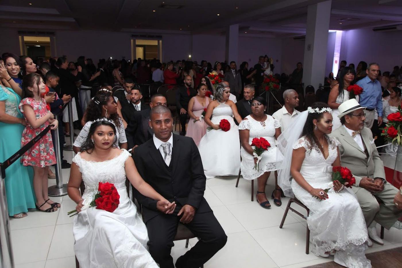 Casais sentados lado a lado em cerimônia em salão #paratodosverem