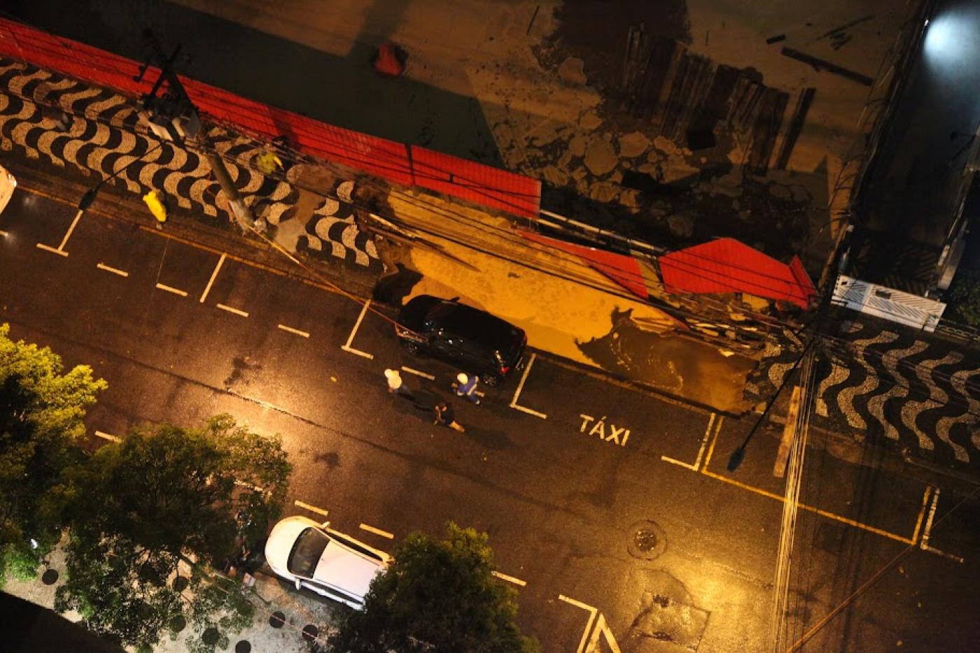 foto aérea mostra trecho de calçada solapado com parte de um veículo pendendo para dentro. Há um terreno vazio ao lado onde está se fazendo uma obra. #paratodosverem 