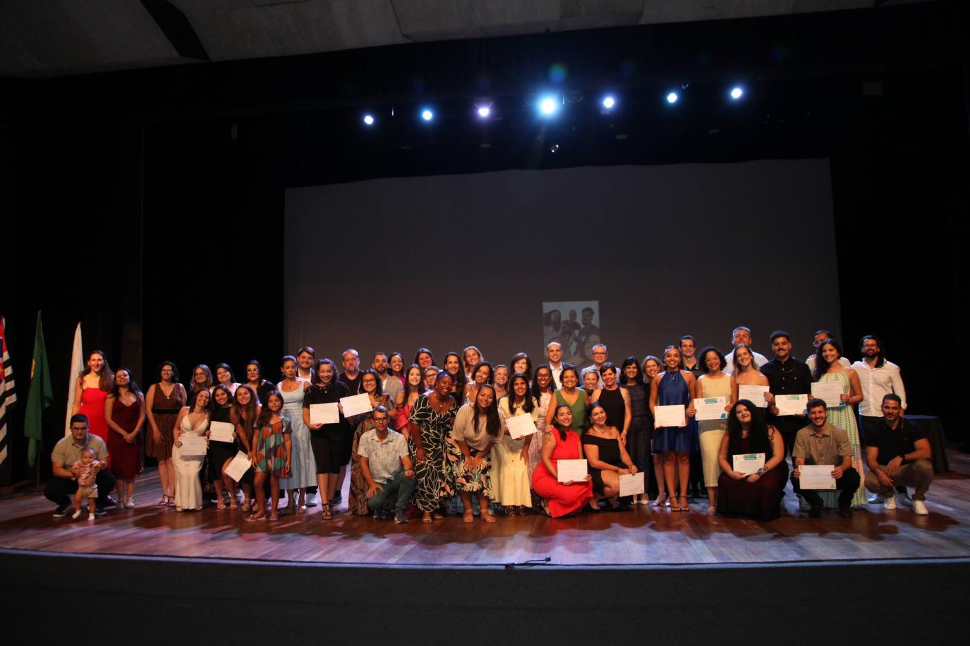 formandos estão em palco posando para foto. #paratodosverem 