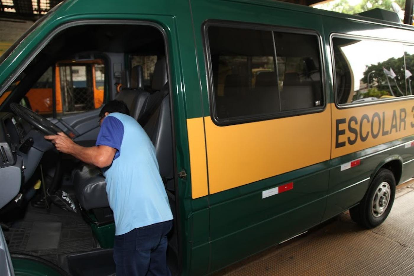 homem está mexendo em banco de condução escolar que está parada. #paratodosverem 