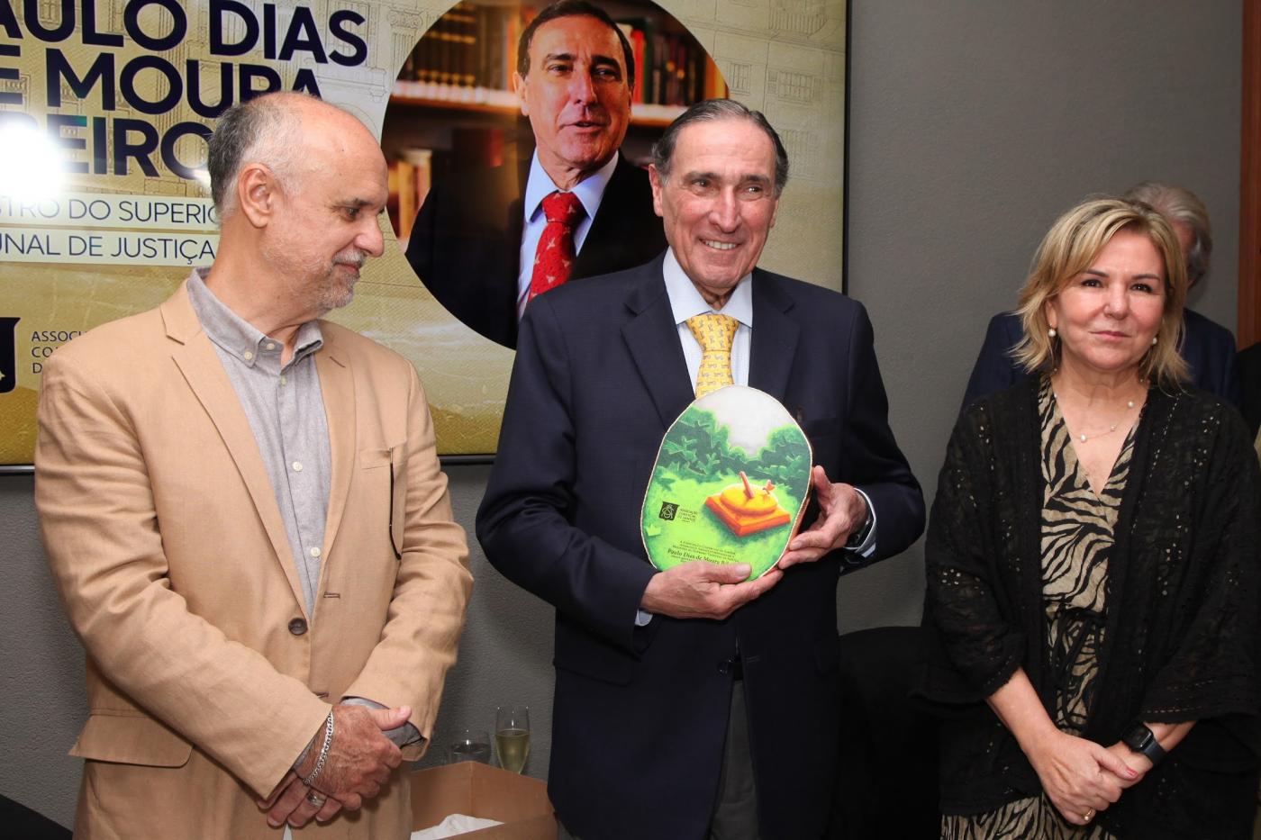 homem segura placa. ele está no meio de duas pessoas. #paratodosverem