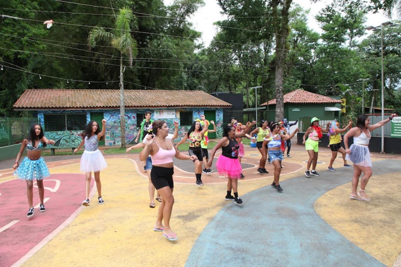 mulheres dançam em quadra ao ar livre. elas fazem uma coreografia. #paratodosverem 