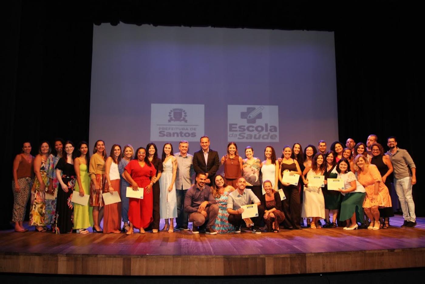turma de formandos posa para foto em palco. #paratodosverem
