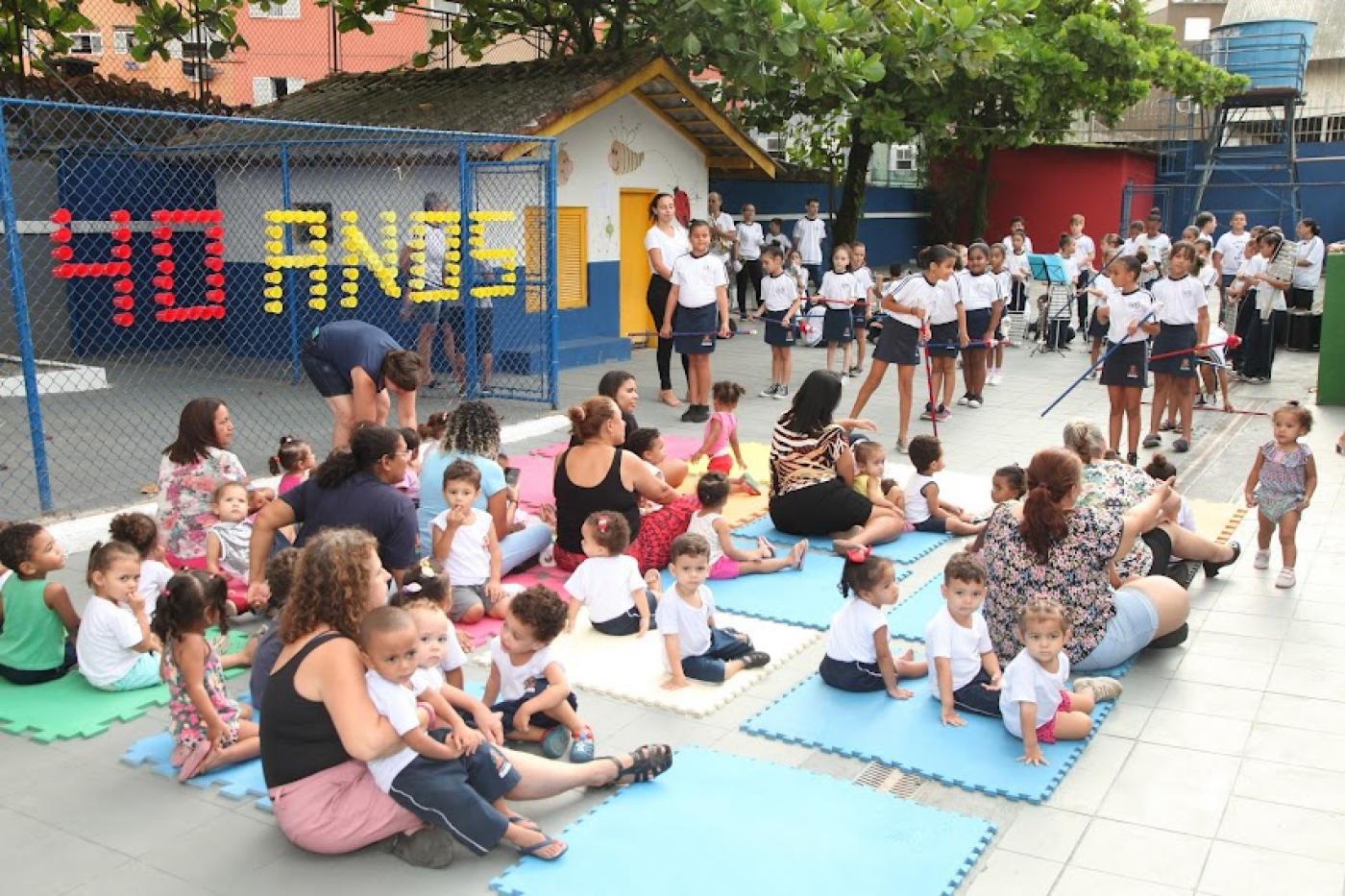 alunos e adultos reunidos em pátio assistindo apresentação de banda. #paratodosverem