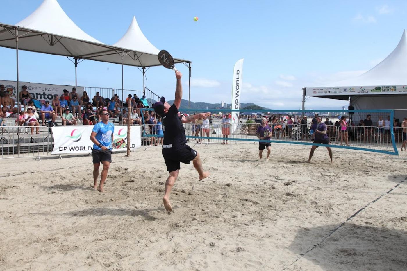 duas duplas jogando beach tennis. A rede está entre elas. #paratodosverem 