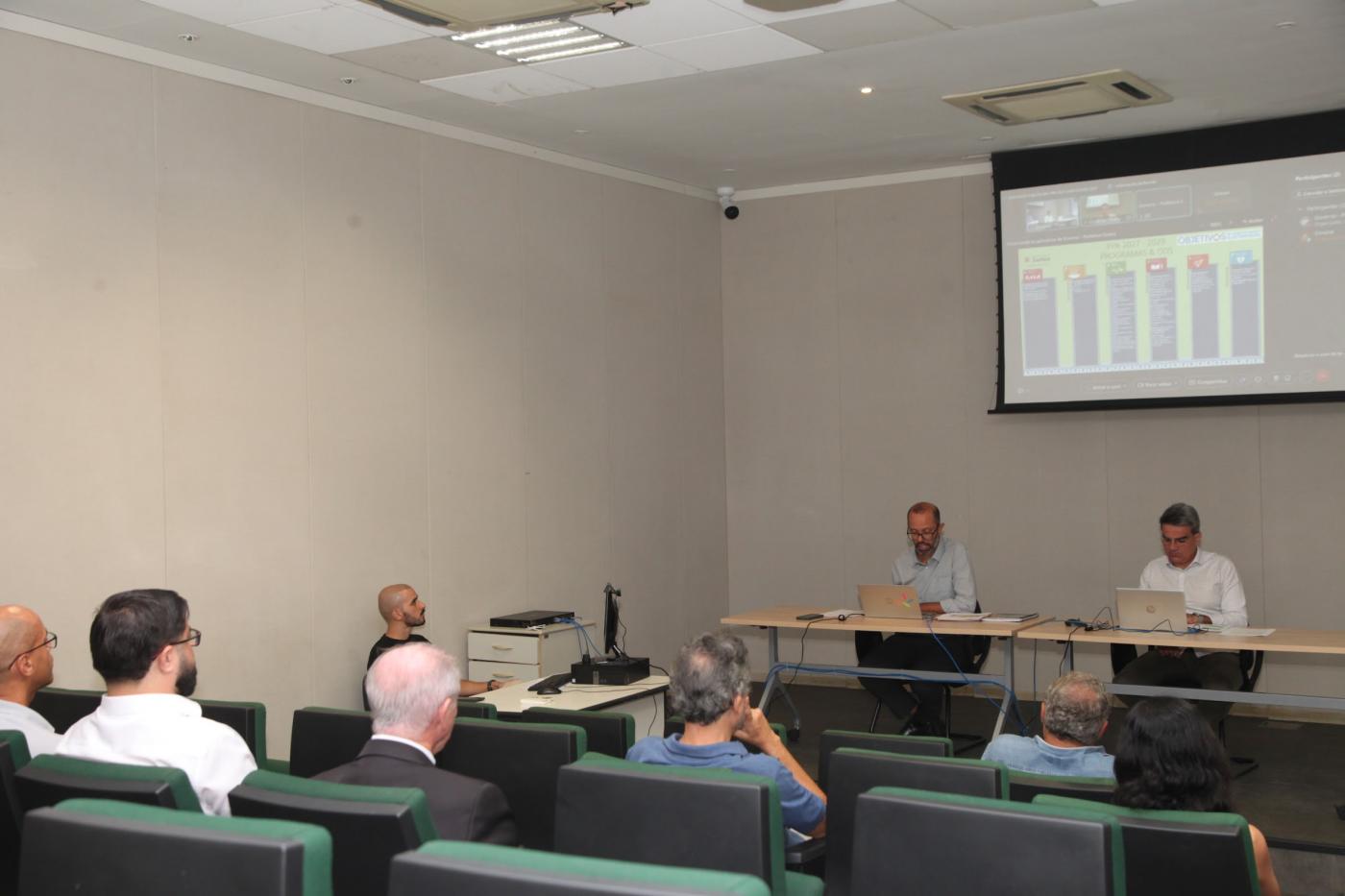 palestra com duas pessoas falando e público sentado. #paratodosverem
