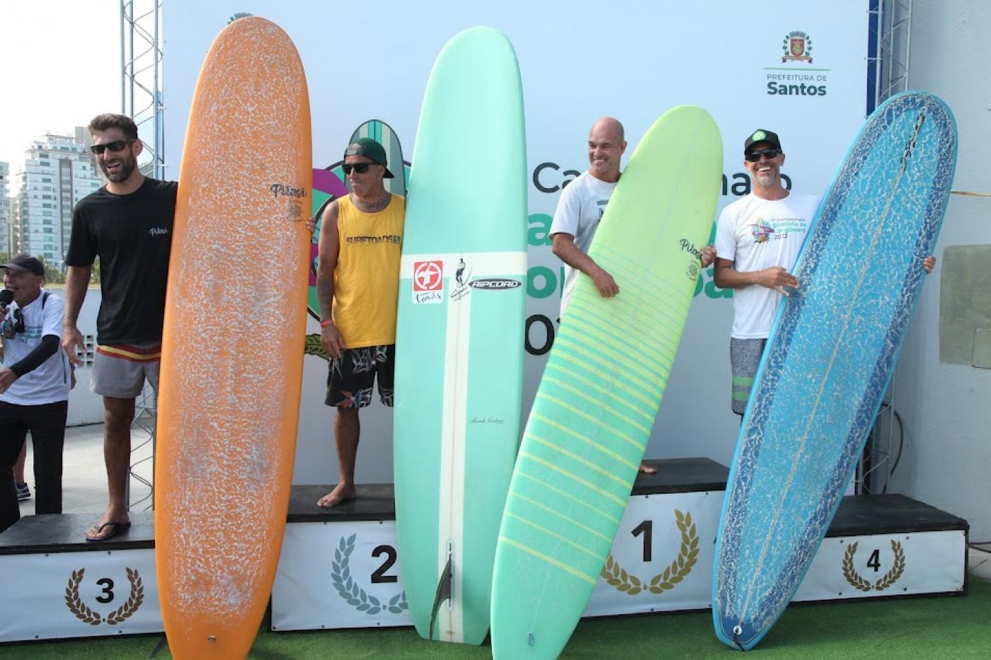 os homens vencedores da categoria open com seus pranchões estão no pódio do número 1 ao 4. #paratodosverem