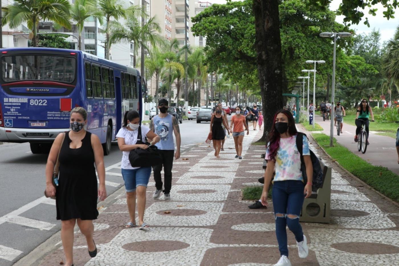 Pessoas andam no calçadão da orla usando máscara. #paratodosverem