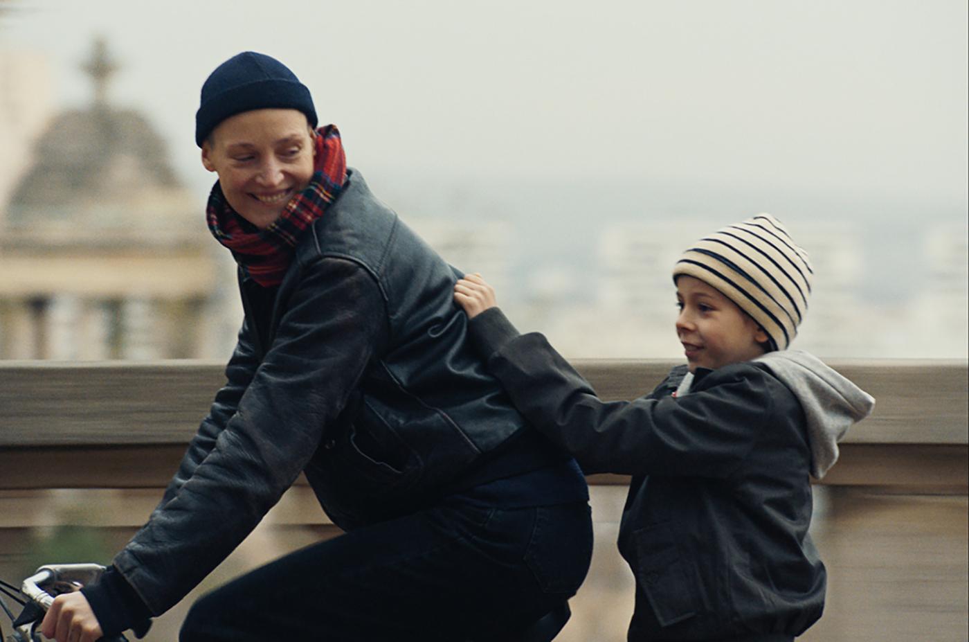 mulher anda de bicicleta com criança na garupa. #paratodosverem