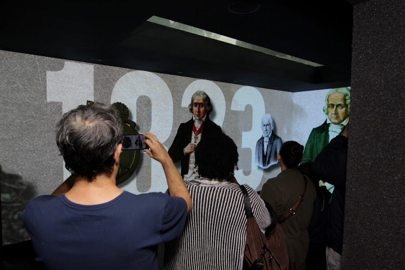 Munícipes tiram fotos de telões com imagens de José Bonifácio. #paratodosverem