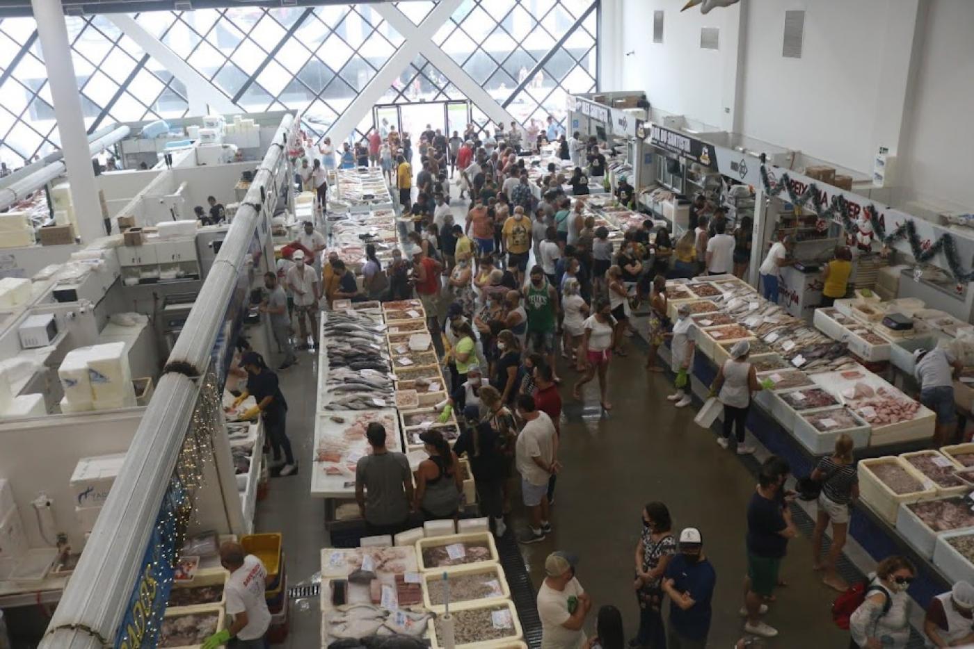 vista geral do mercado de peixe, com boxes vistos de cima e o público circulando. #paratodosverem