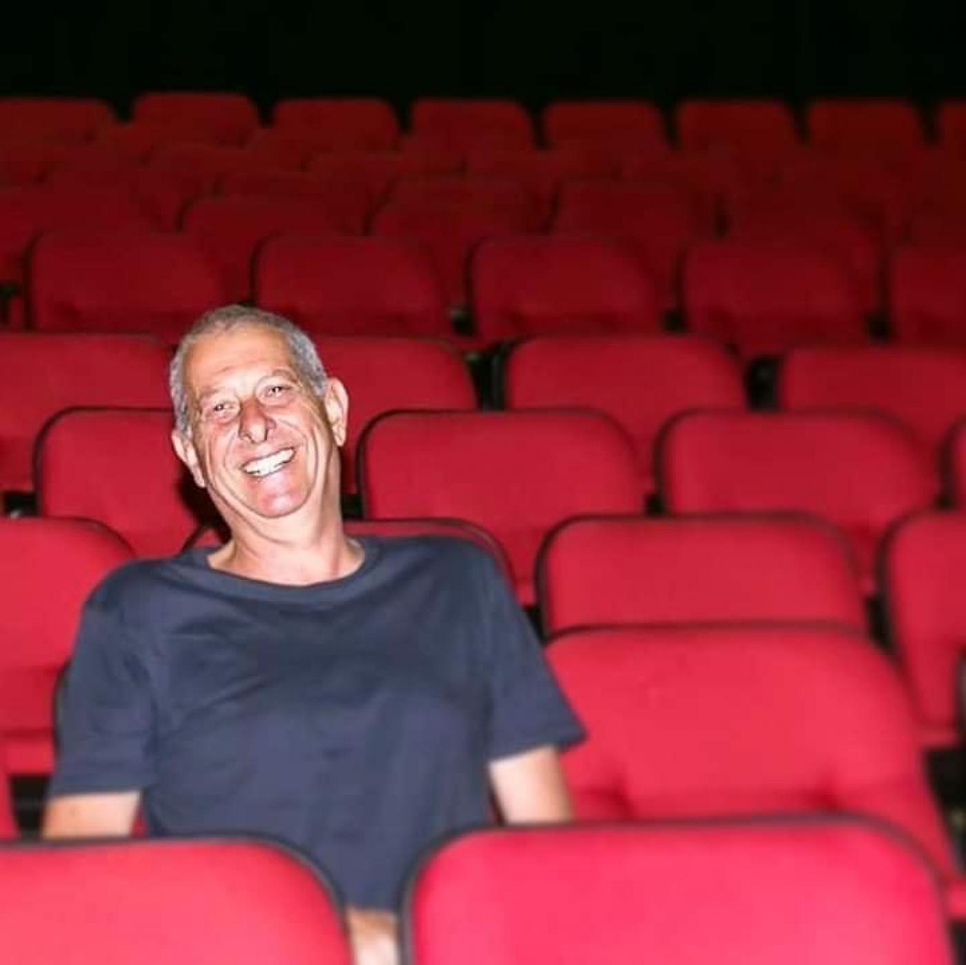 Alcides Mesquita sentado na plateia de um teatro sozinho. #Paratodosverem