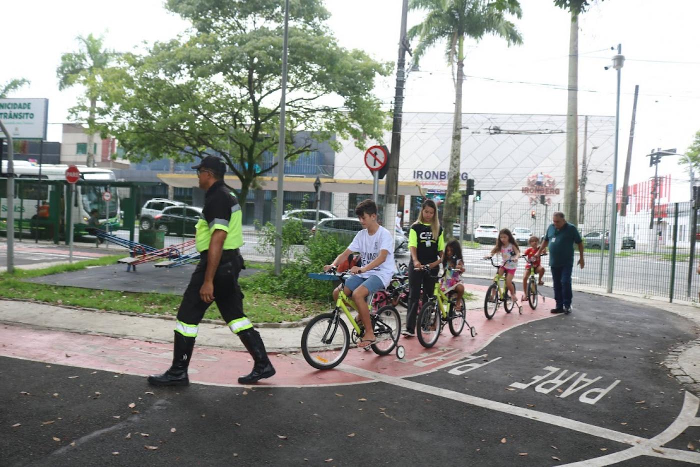crianças de bicicleta seguem agente #paratodosverem