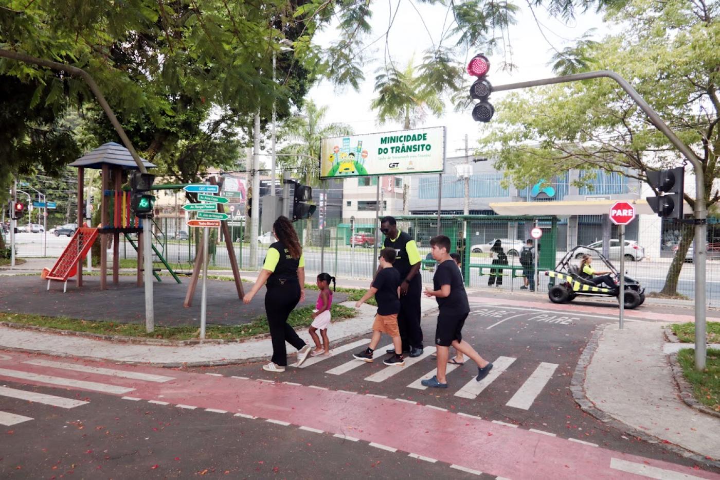 monitores ajudam crianças a atravessar a rua #paratodosverem