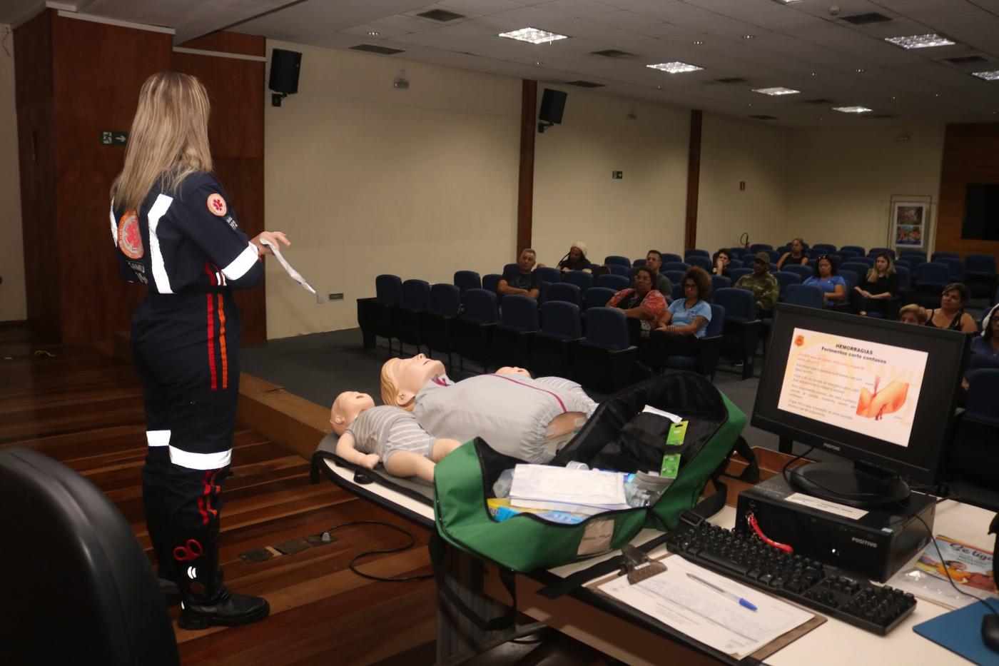 enfermeira com uniforme dá palestra em auditório. #paratodosverem