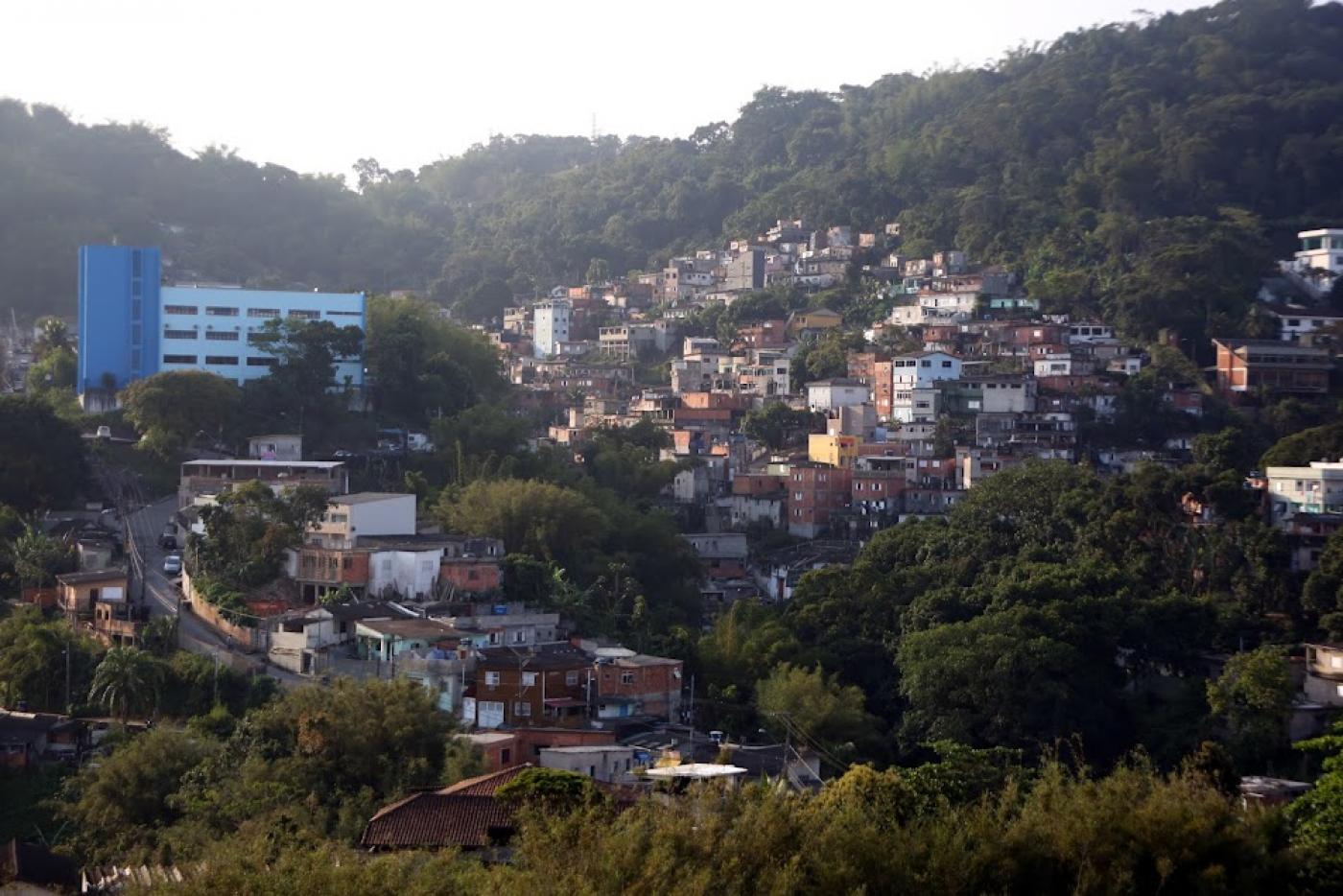 vista geral do morro com casas e uma edificação principal que é uma escola, à esquerda. #paratodosverem