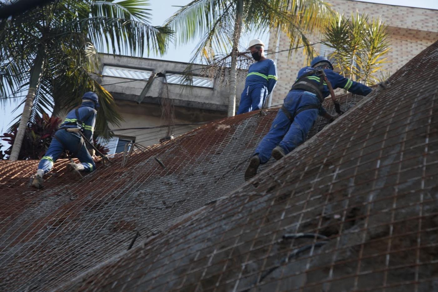 Homens estão trabalhando em encosta de morro. #Paratodosverem