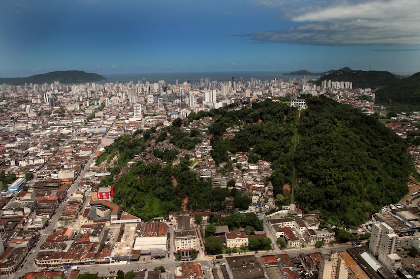 vista geral da cidade com massa de vegetação de morro à direita e a cidade em torno e à esquerda. #paratodosverem